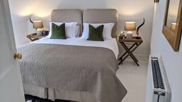 A neatly arranged bedroom with a large bed, two bedside tables, and a radiator.