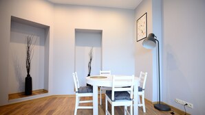 A dining area with a round table, four white chairs, a black vase, and a floor lamp. - Victus Apartamenty - Penthouse 2 (Sopot)