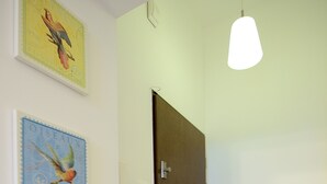 A hallway with a dark door, a hanging light fixture, and three wall-mounted bird-themed postage stamps. - Victus Apartamenty - Penthouse 2 (Sopot)
