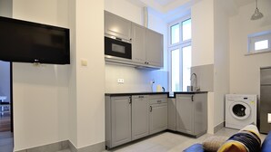 A modern kitchen with grey cabinets, a built-in oven, and a washing machine. - Victus Apartamenty - Penthouse 2 (Sopot)