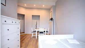 A bedroom with a bed, a dresser, a dining table with chairs, and a lamp. - Victus Apartamenty - Penthouse 2 (Sopot)