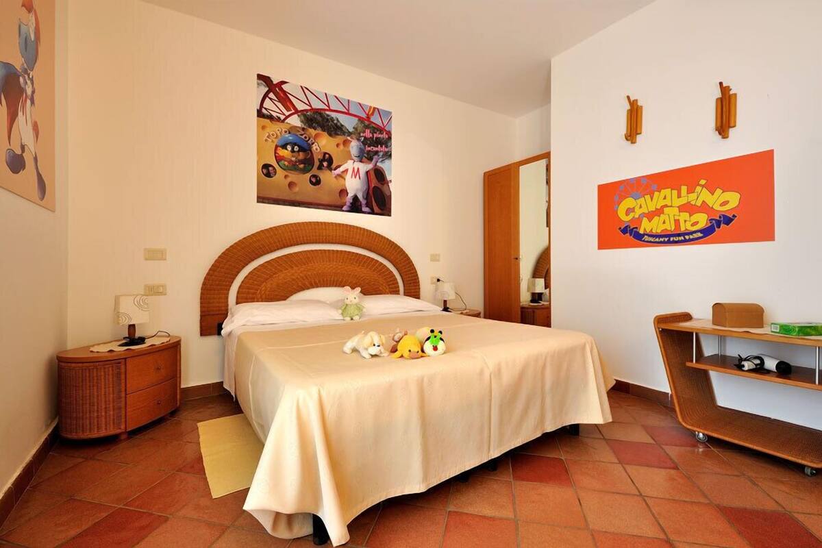 Ein Hotelzimmer mit einem Bett, einem Nachttisch, einer Kommode, einem Spiegel und einer Wand mit einem Poster.