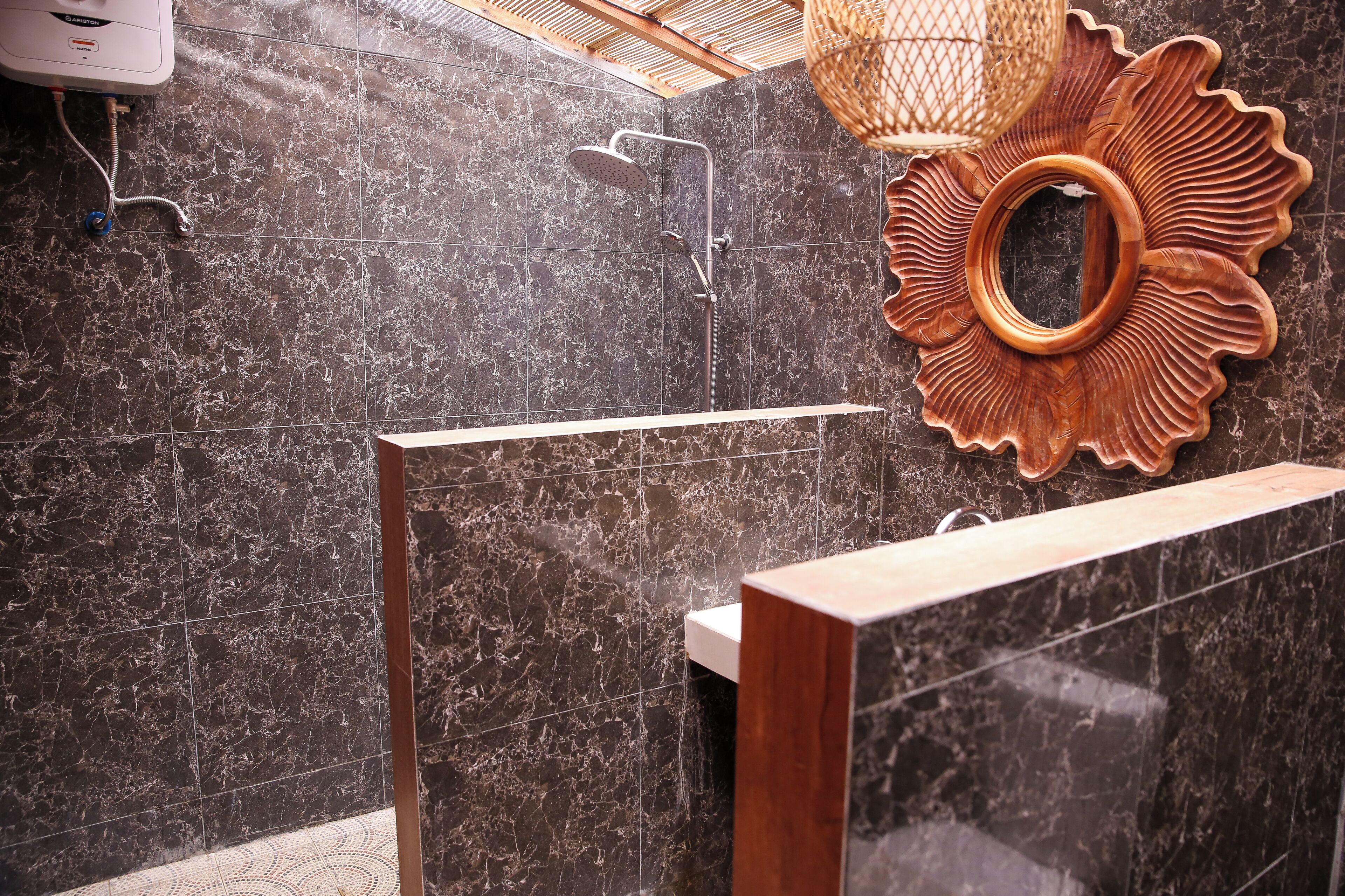 A modern bathroom with a shower, a wooden bench, and a decorative mirror.