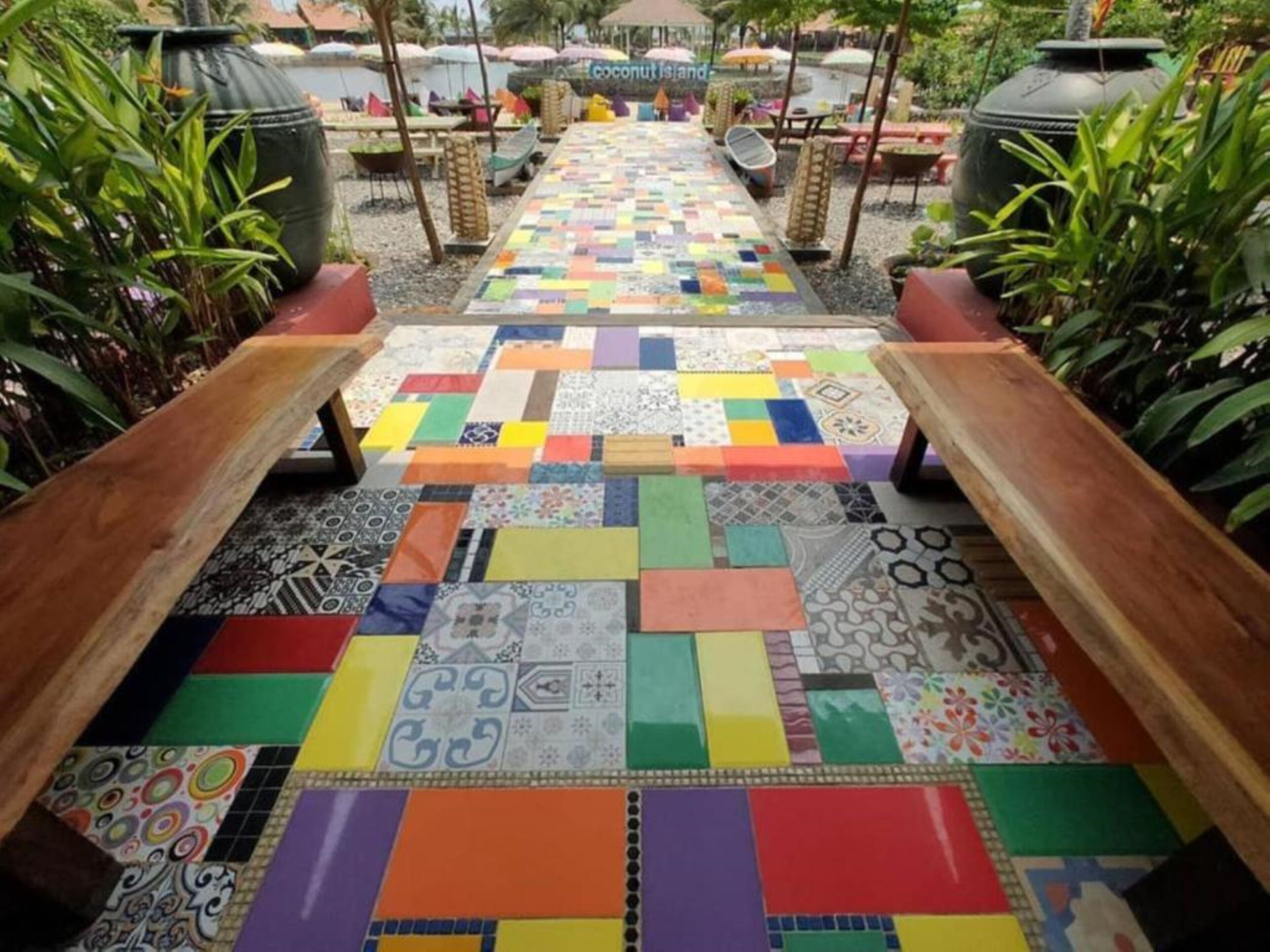 A pathway with colorful tiles leading to a seating area with umbrellas.
