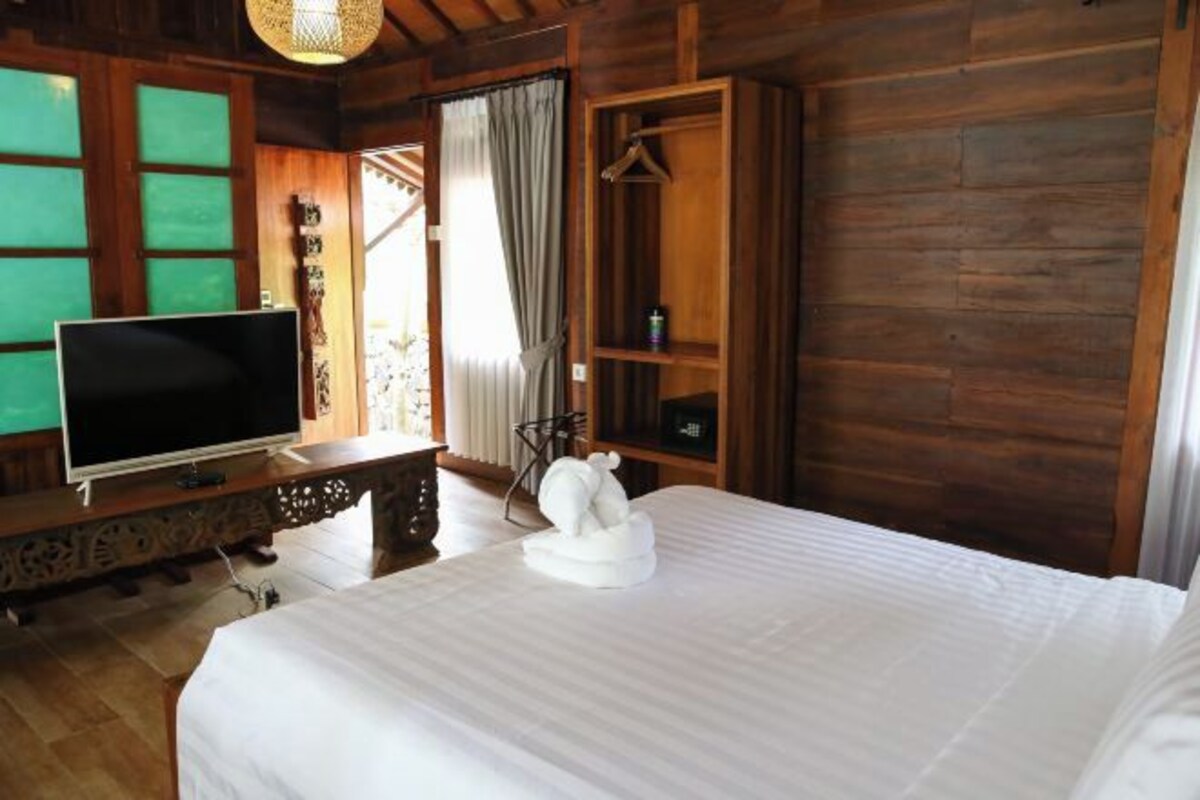 A wooden room with a bed, a television on a wooden cabinet, and a wardrobe.