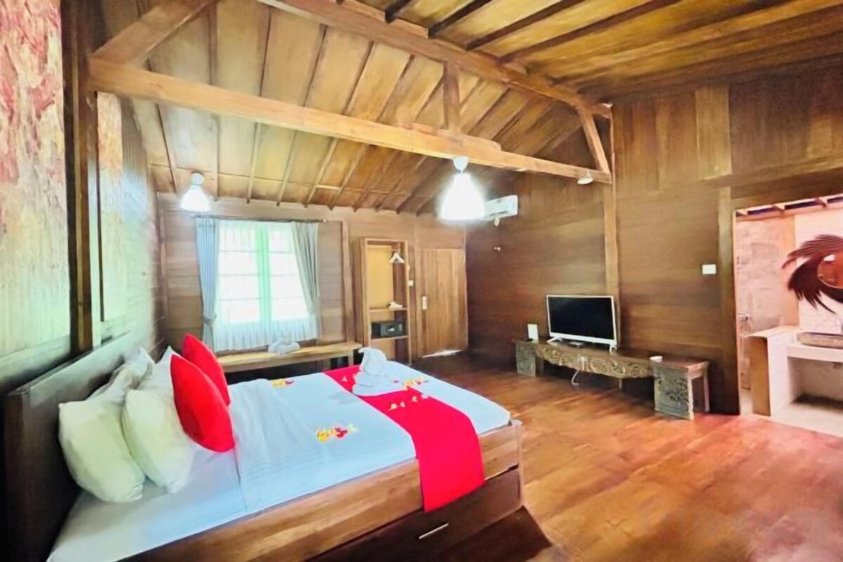 A wooden room with a bed, a television, and a desk.