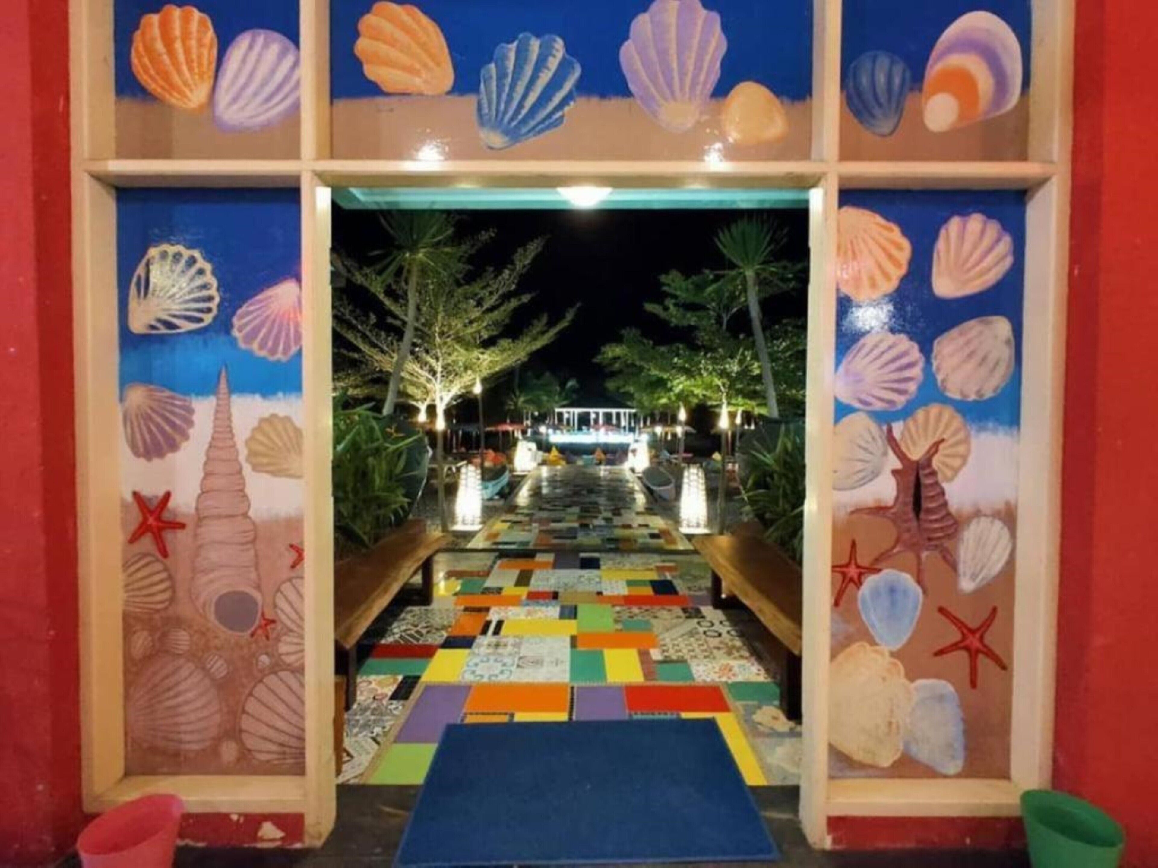 A hallway with a colorful mosaic floor leading to a pool area, decorated with seashells and starfish.