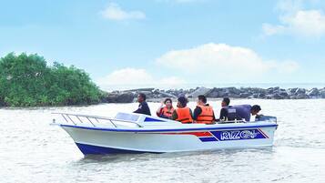 A boat with passengers wearing life jackets on a calm body of water.