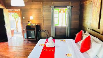 Una habitación de madera con una cama, una mesita con una lámpara y una ventana con cortinas.