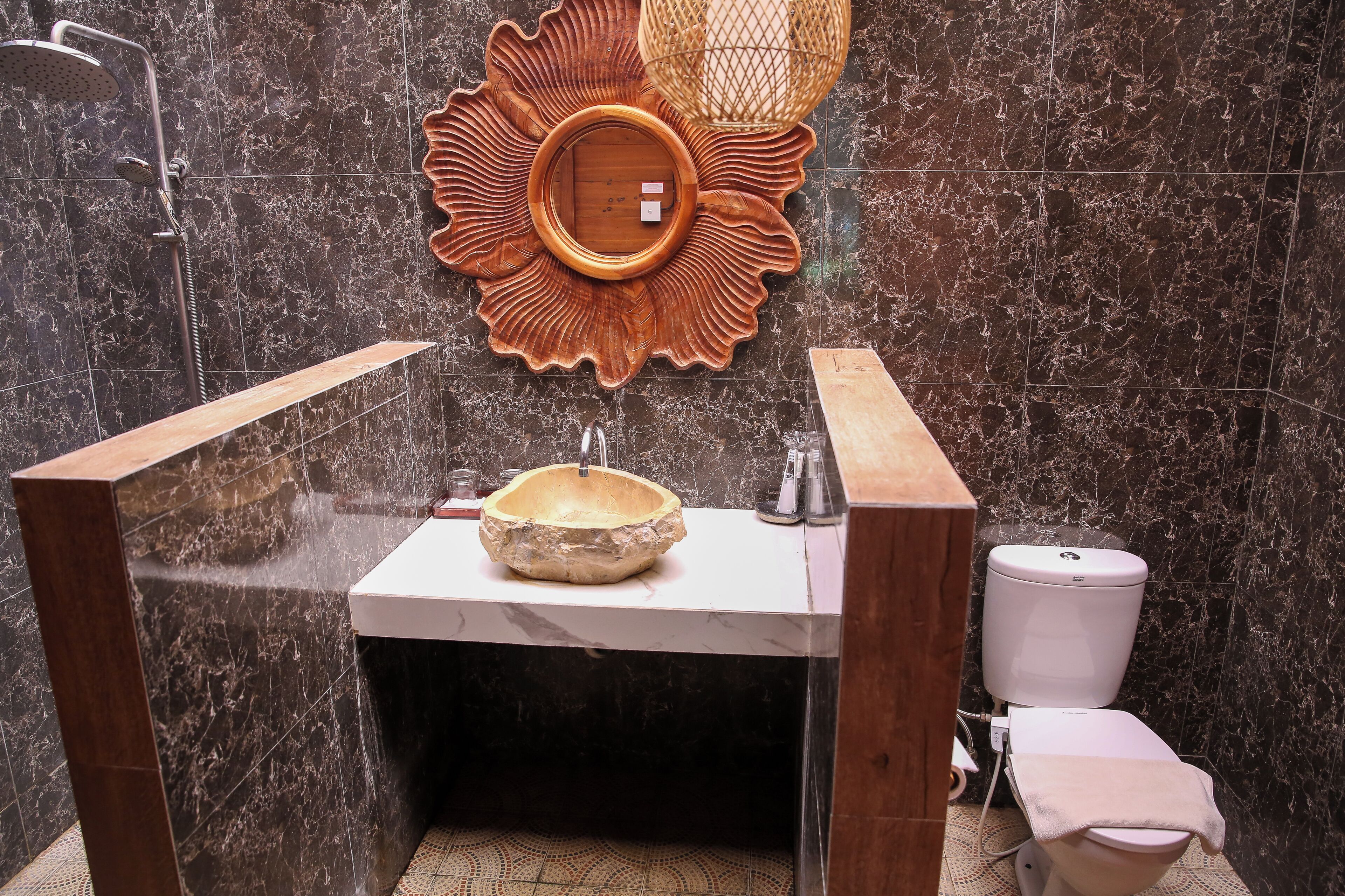 Ein Badezimmer mit Marmorwaschbecken, einer Holzwaschschale, einer Duschbrause und einer Toilette.