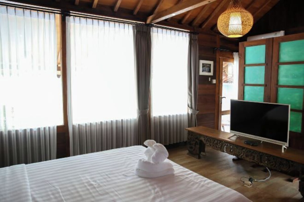 A hotel room with a bed, a television, and a window with curtains.