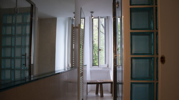 A hallway with a glass door, a bench, and a radiator.
