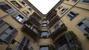 A multi-story building with balconies, air conditioning units, and potted plants.