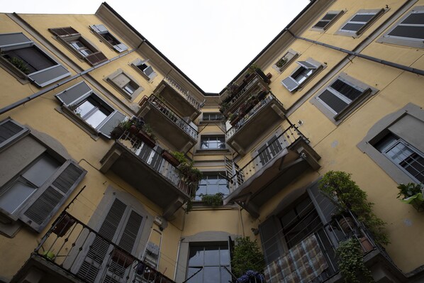 A multi-story building with balconies, air conditioning units, and potted plants.