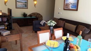 A living room with a dining table set for two, a sofa, and a stone fireplace. - Casa Goncalito Ground floor (Bordeira)