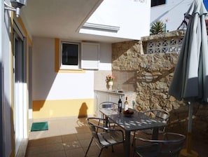 Un espace patio avec une table et des chaises, un mur en pierre et une petite fen être.