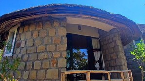 A stone building with a wooden porch and a thatched roof. - Bethan Amba ecovillage (Lalibela)