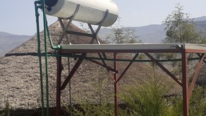 A telescope on a metal stand with a metal table in front, set against a mountainous landscape. - Bethan Amba ecovillage (Lalibela)
