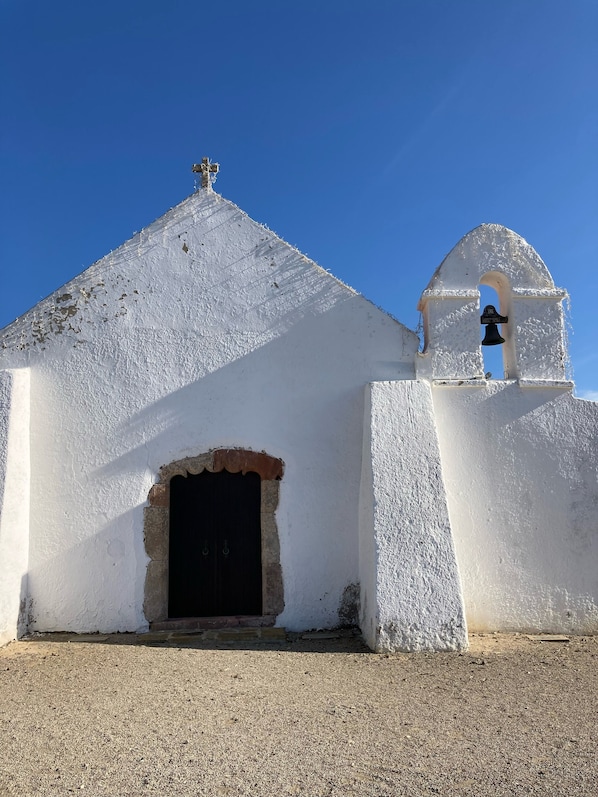 A white church with a bell tower and a small entrance.