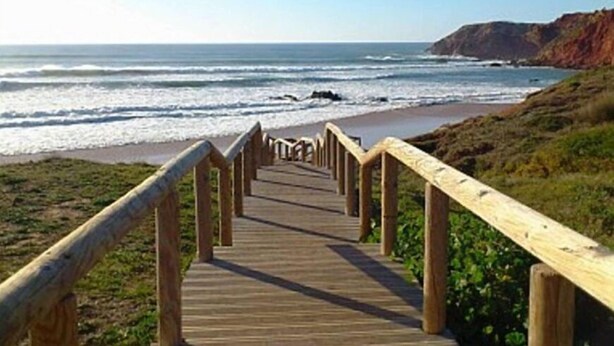 A wooden boardwalk leading to a beach with waves and cliffs in the background. - Casa rustica, Apartment with balcony (Bordeira)