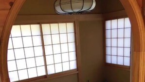 Una habitación japonesa tradicional con suelo de tatami, puertas correderas shoji y una lámpara colgante.