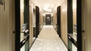 A hotel corridor with patterned flooring, mirrored doors, and a central chandelier. - ST Signature Jalan Besar, SHORT OVERNIGHT, 8 hours: 11:59PM-8AM (Singapore)