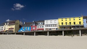 A row of colorful buildings along a beach, including a restaurant and a hotel.