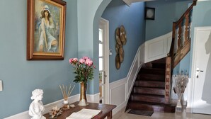 A hallway with a wooden table, a painting, and a vase of flowers. - Entre Terre et Mer (Plougoulm)