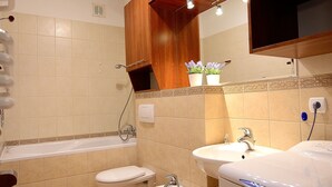 A bathroom with a bathtub, two sinks, a toilet, and a shower. - Victus Apartamenty - Petit (Sopot)