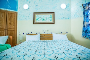 Habitación de hotel con cama, un armario de madera, un cuadro en la pared y una colcha estampada.