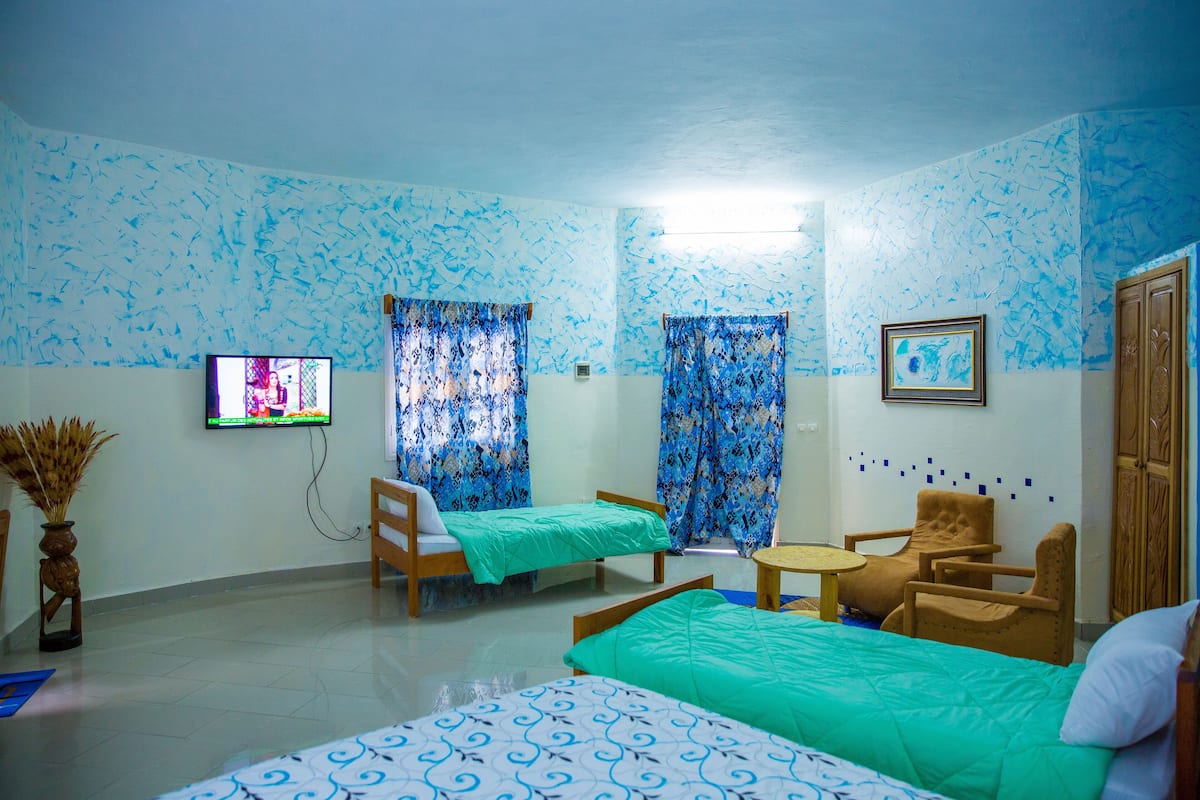 A room with two beds, a TV, a wooden chair, and a small table.