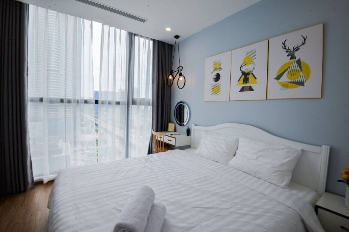 A hotel room with a large bed, a bedside table, a mirror, and artwork on the wall.