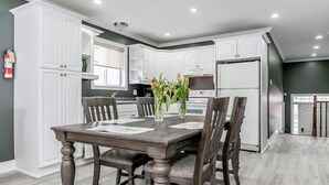 A modern kitchen with white cabinets, a dark wooden dining table, and chairs. - Beach1 Riverfront Resort - #32 - Wasaga Beach (Wasaga Beach)