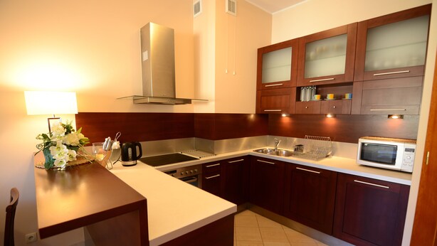 Una cocina moderna con armarios de madera, electrodomésticos de acero inoxidable y encimera blanca.