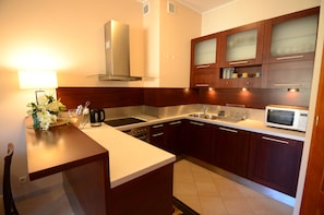 A modern kitchen with wooden cabinets, stainless steel appliances, and a white countertop. - Victus Apartamenty - Platinium (Sopot)