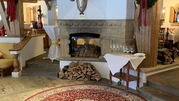 A rustic interior with a stone fireplace, a mounted deer head, and a red patterned rug.