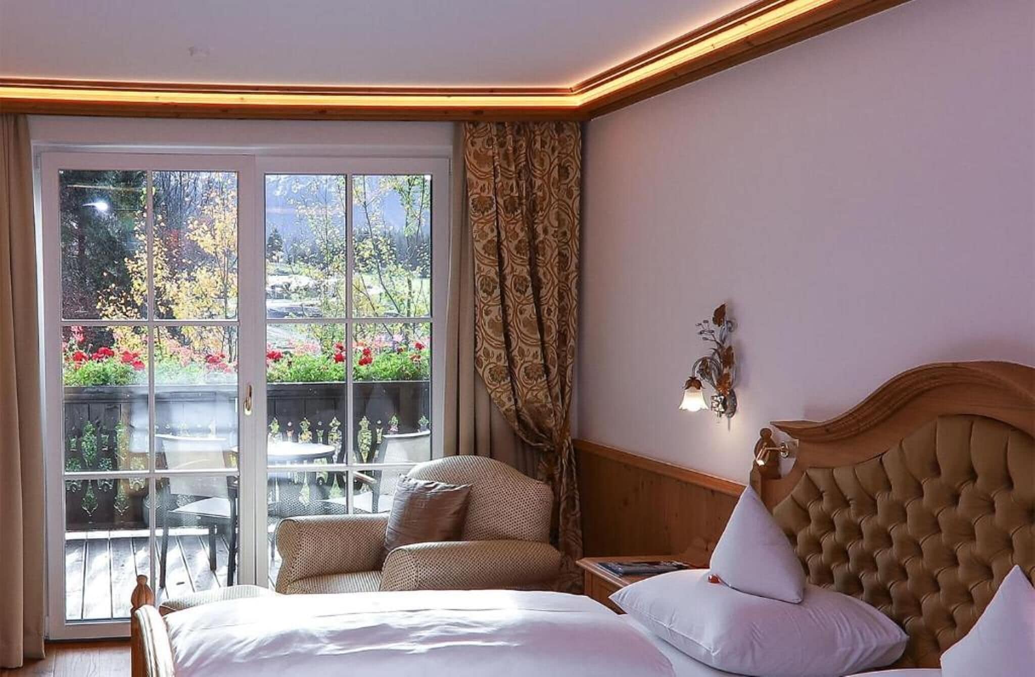 A hotel room with a large window, a bed, a nightstand, and a chair.