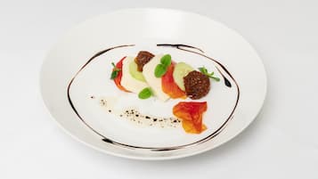 Ein weißer Teller mit einem Dessert aus Obstscheiben, einer Kugel Sahne und Schokoladenguss.