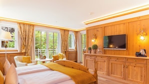 Une chambre avec un grand lit, une télévision, des meubles en bois et une fenêtre avec des rideaux.