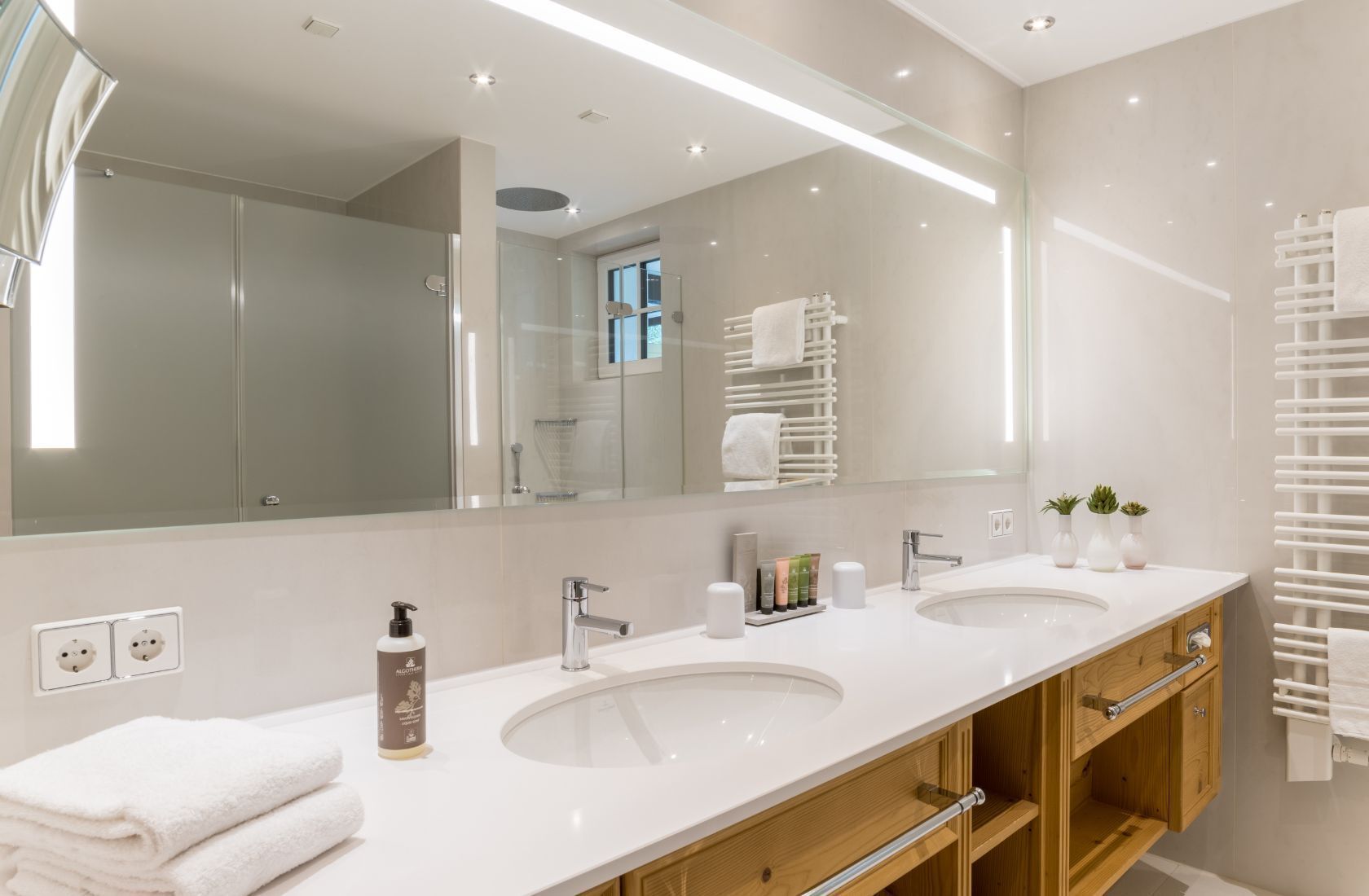 Une salle de bain moderne avec deux lavabos, un grand miroir et un porte-serviettes.