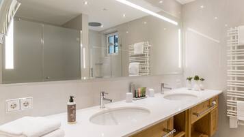 Une salle de bain moderne avec deux lavabos, un grand miroir et un porte-serviettes.