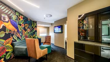A lobby with a colorful mural, a television, a bar area, and seating.