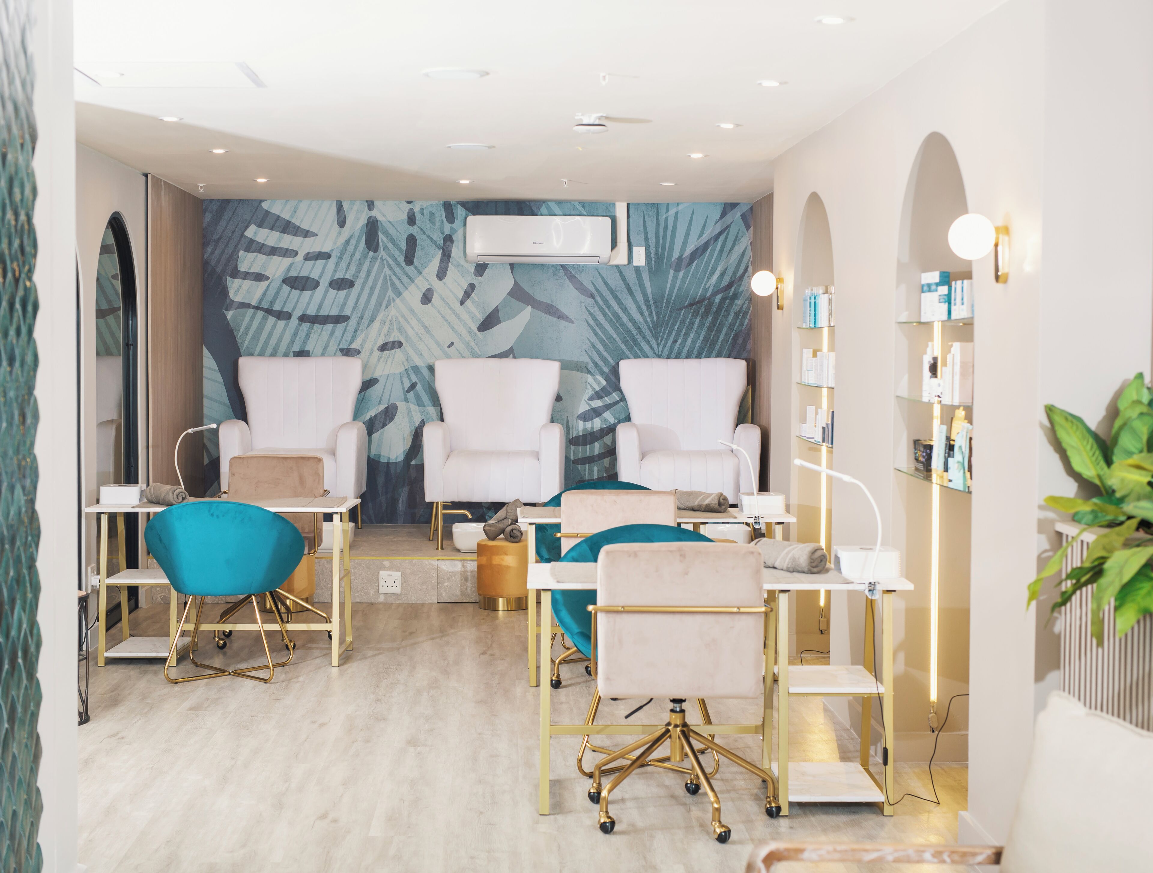 A modern spa room with two white armchairs, a blue chair, and a massage table.