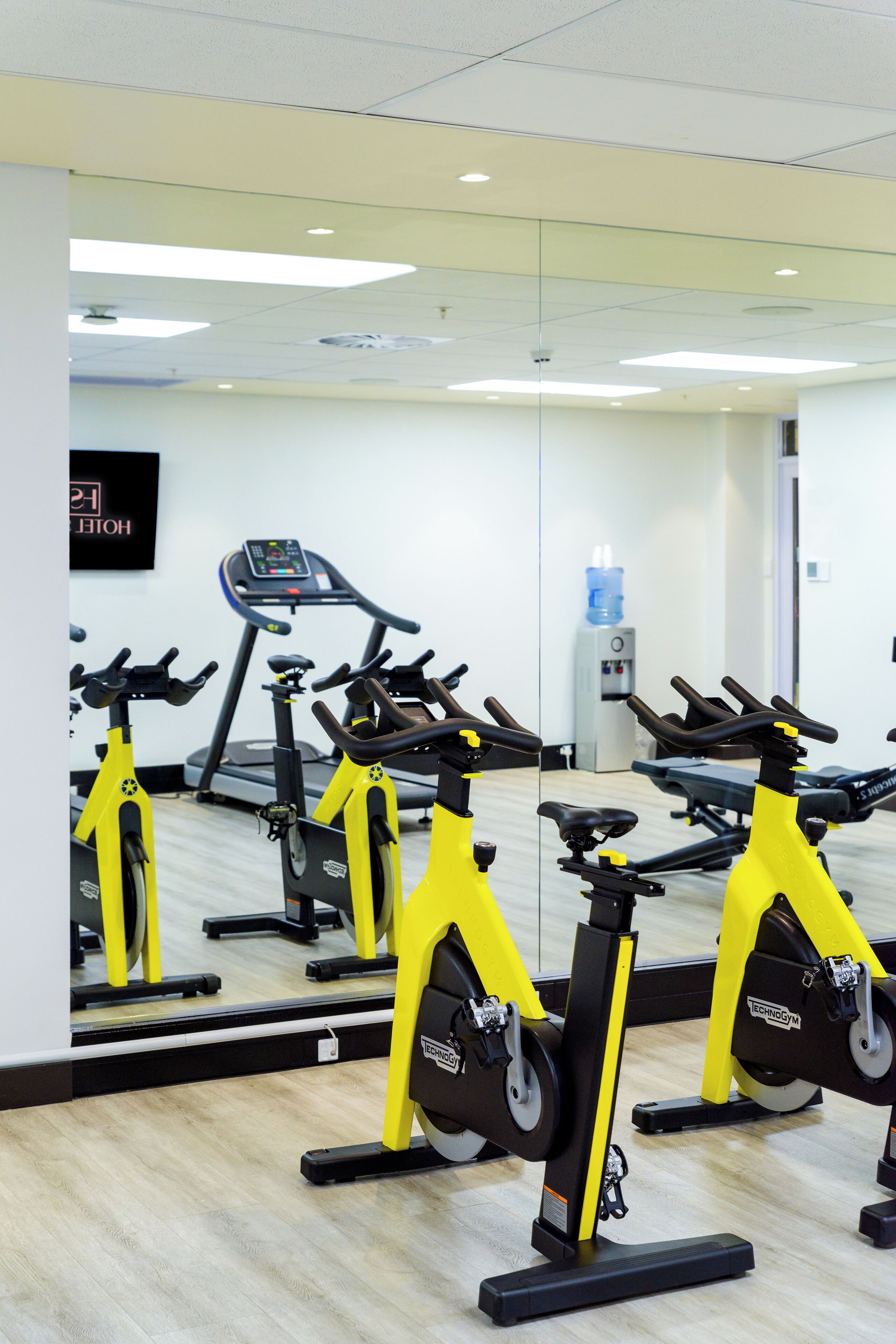 A gym with stationary bikes, a treadmill, and a water dispenser.