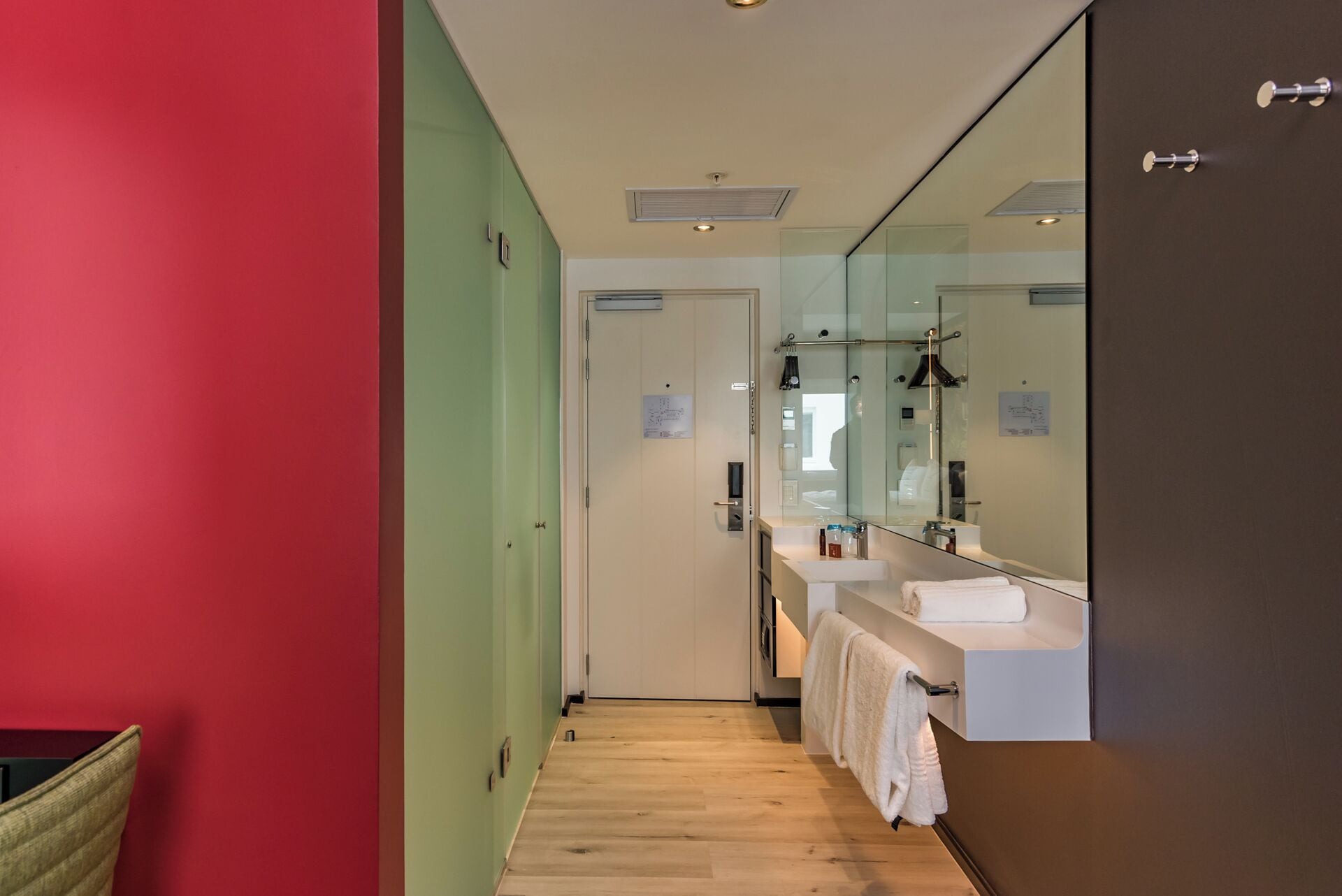 Une salle de bain moderne avec un plancher en bois, un lavabo blanc et un grand miroir.