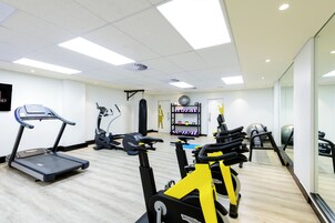 Un gimnasio con cintas de correr, bicicletas estáticas y varios equipos de ejercicio.