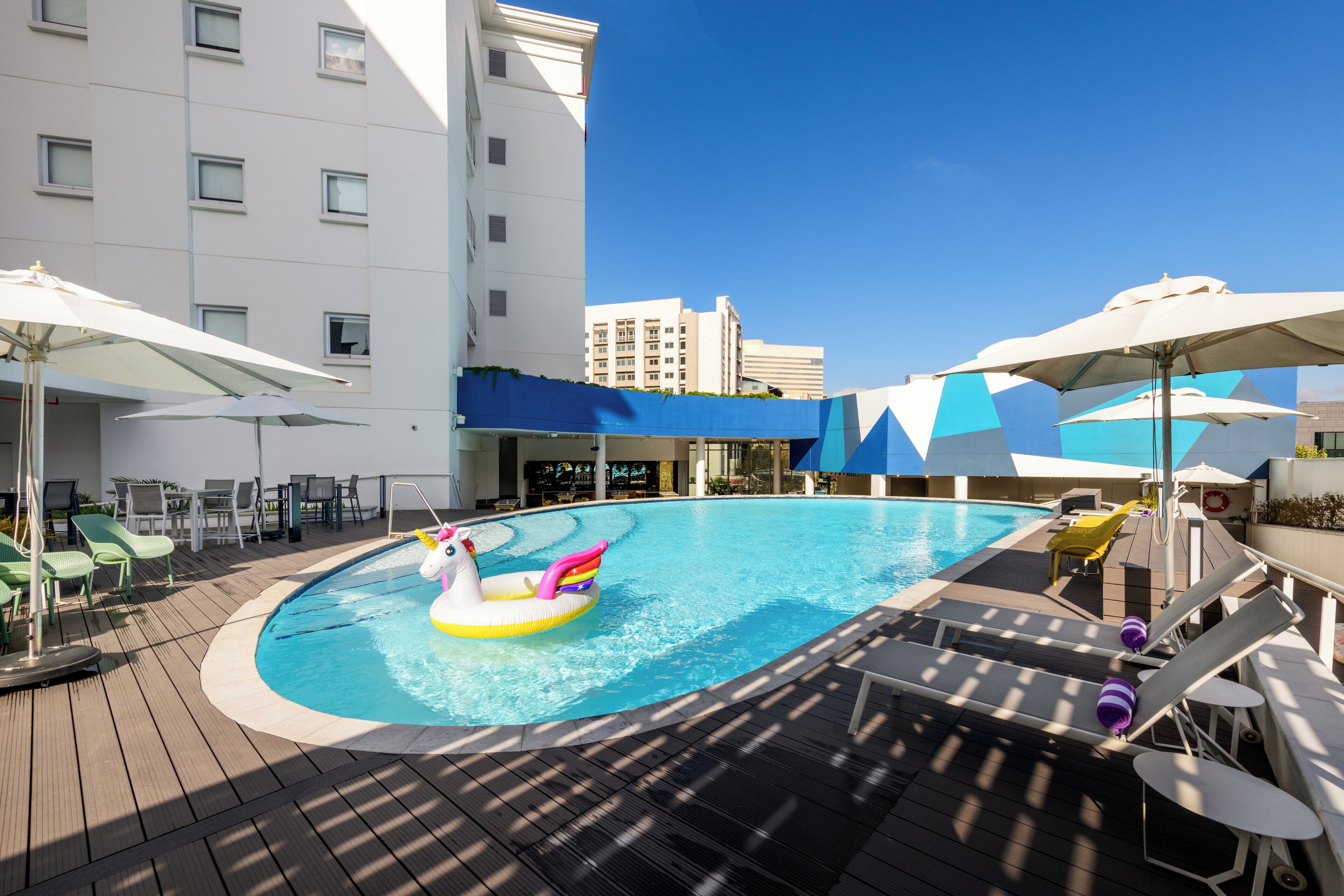 A pool area with lounge chairs, umbrellas, and a colorful inflatable float.