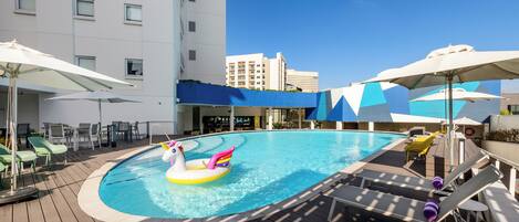 A pool area with lounge chairs, umbrellas, and a colorful inflatable float.