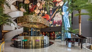 Een weelderige lobby met een centrale bar, een spiraaltrap en een groot muurschildering.