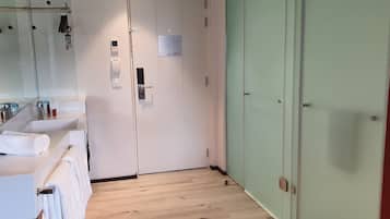 Un baño moderno con cabina de ducha de vidrio, un lavabo blanco con una toalla y una puerta verde.